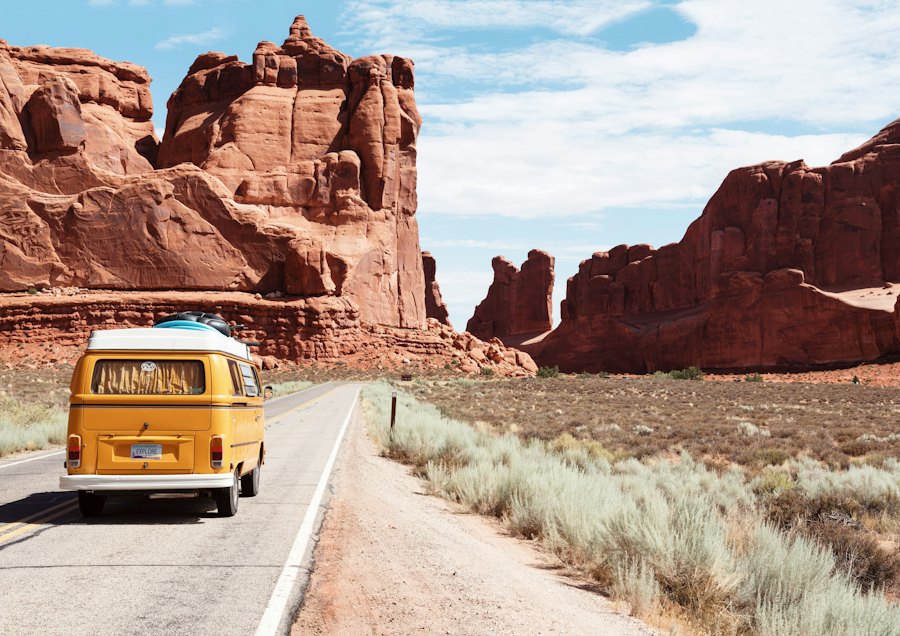 Van driving along an open road through desert scenery